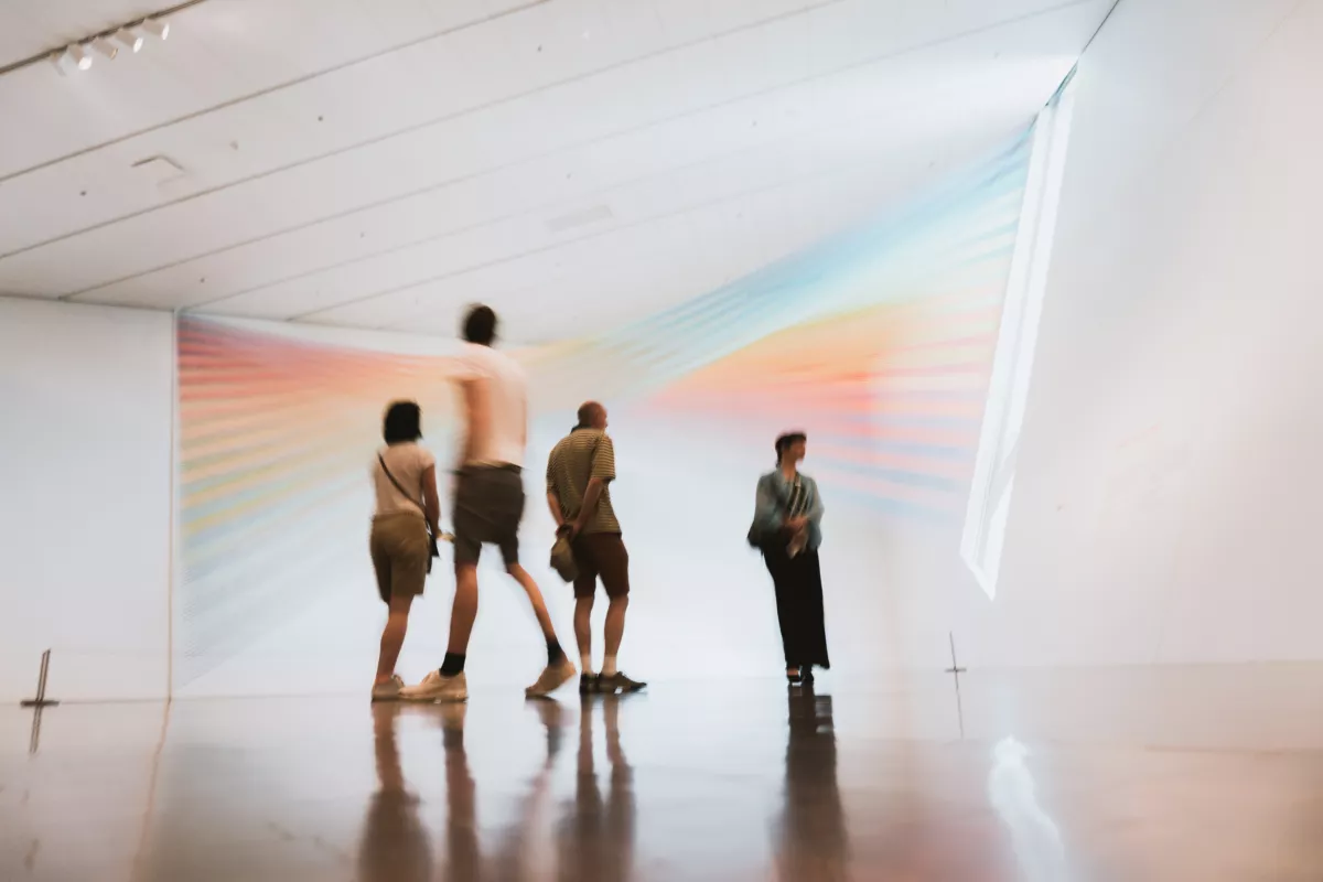 People in a museum with a light projection on the background