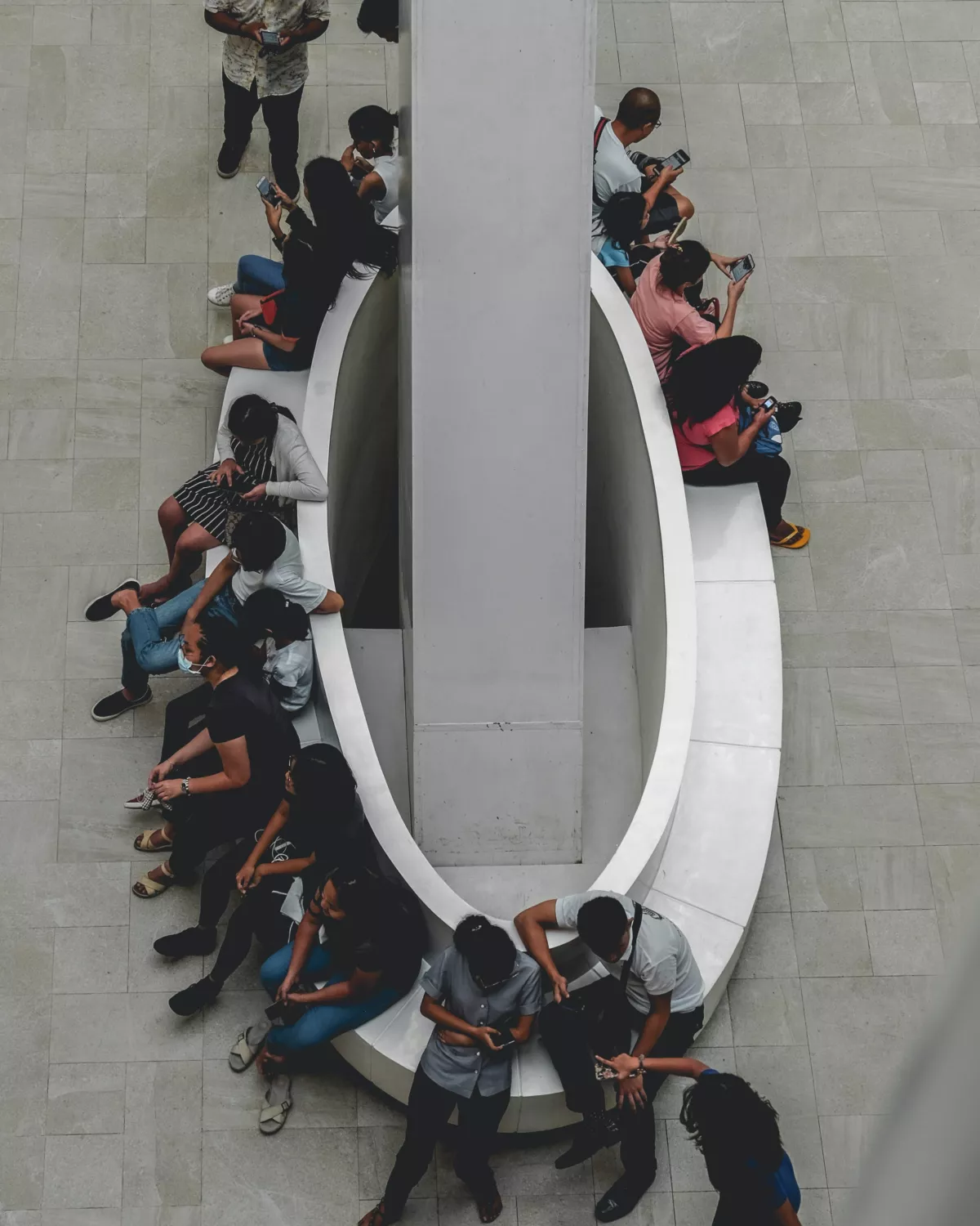 Groep jongeren (Gen Z) zit op een bankje, ze kijken allemaal naar hun smartphones. Dit is het publiek van de toekomst.