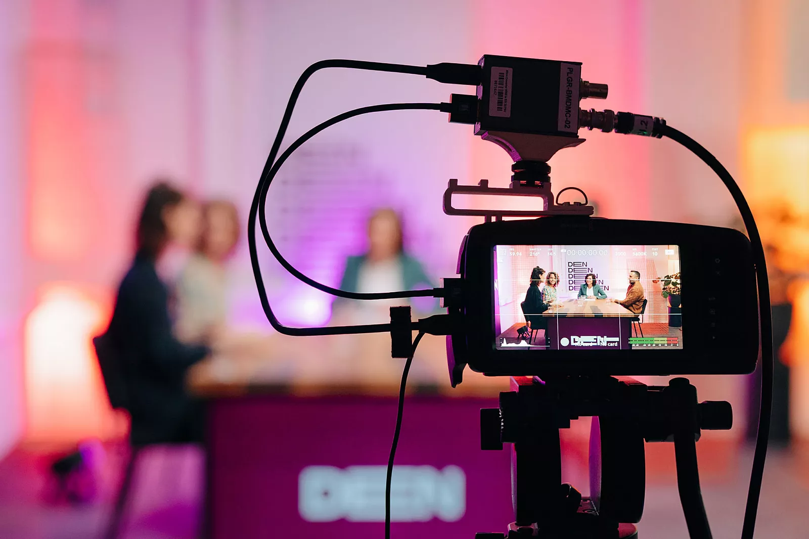 Foto van mensen aan aan tafel op een camera scherm, DEN conferentie 2023