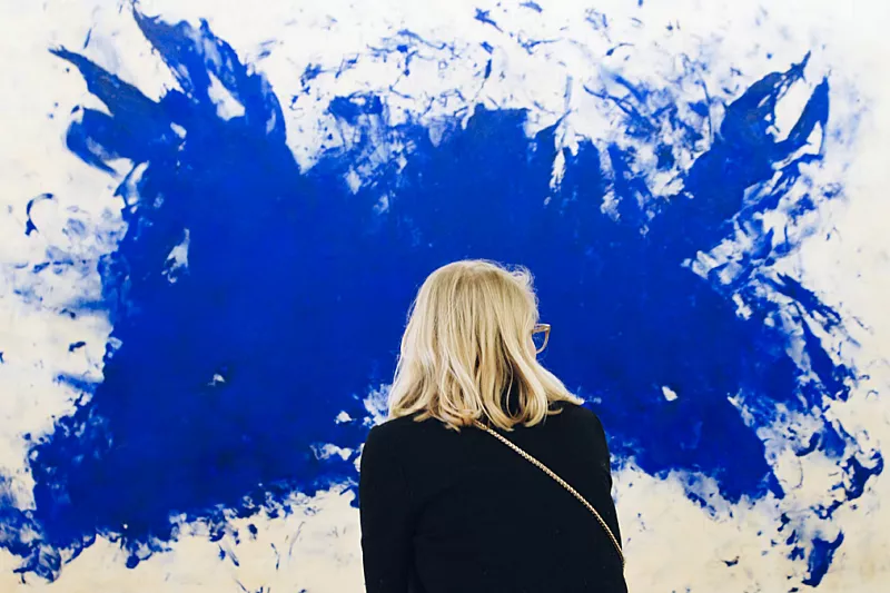 Woman is standing in front of a blue and white artwork